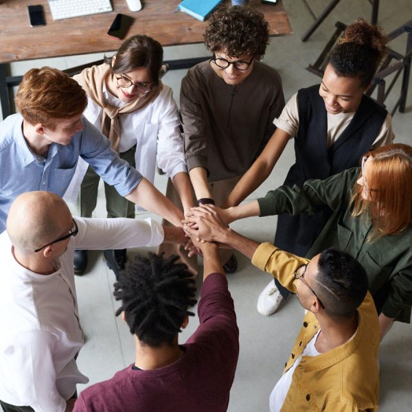 Grupo de jovenes y coach unidos con sus manos
